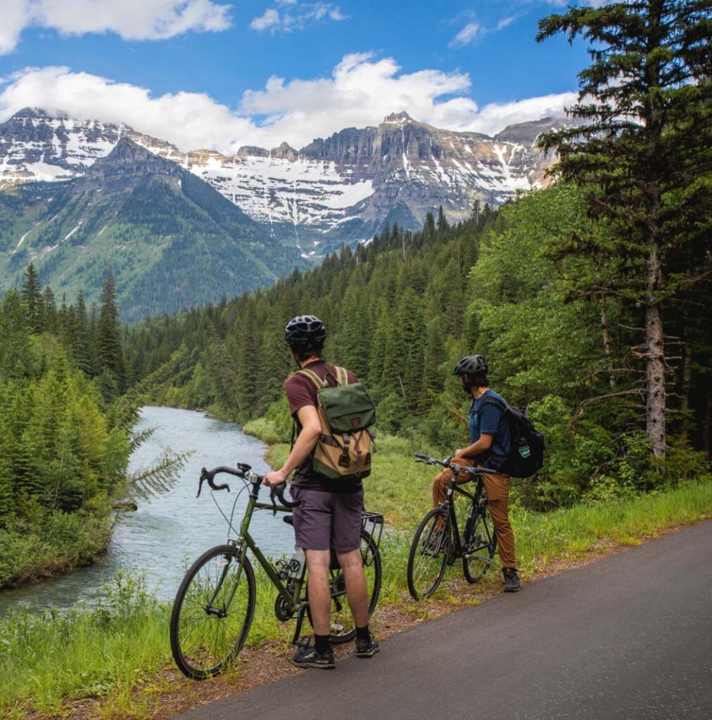 Bikers admiring the view of mountains and a river - an eco-friendly travel activity